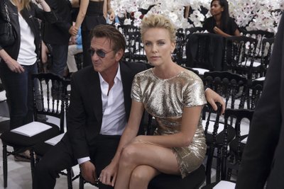 Actors Sean Penn and Charlize Theron pose to the French fashion house Christian Dior Haute Couture Fall/Winter 2014-2015 fashion show by Belgian designer Raf Simons in Paris