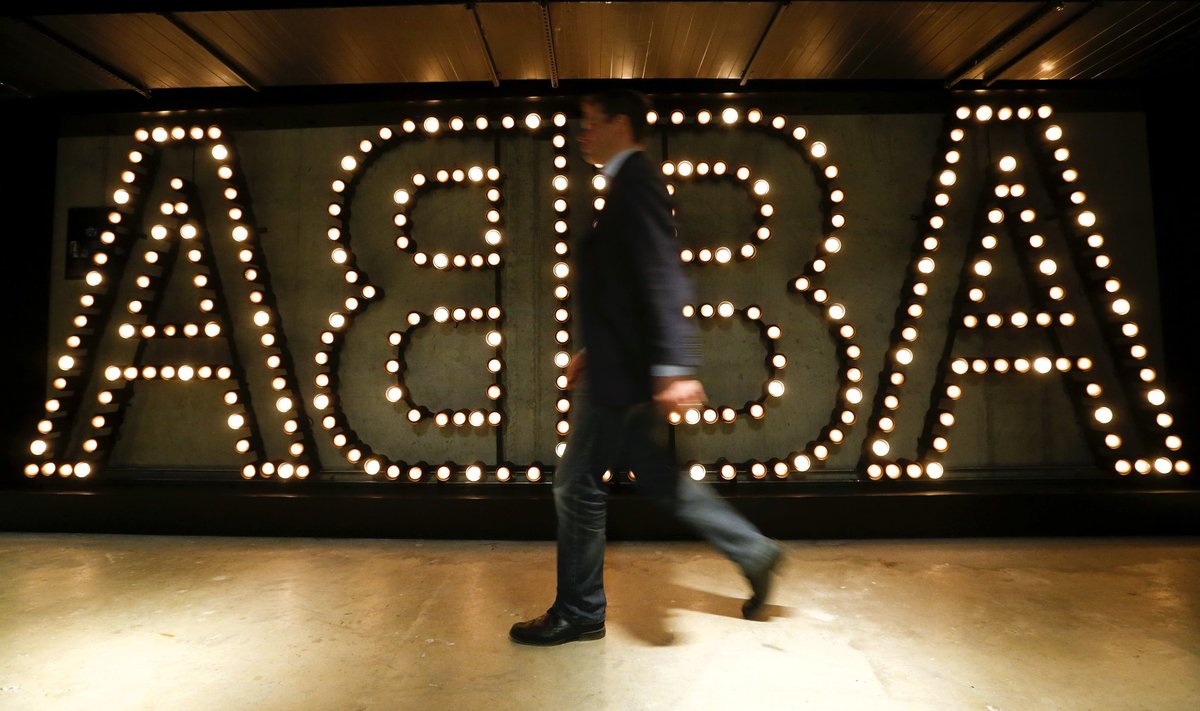 A man walks past the lit logo of the legendary Swedish pop group ABBA at new ABBA Museum in Stockholm