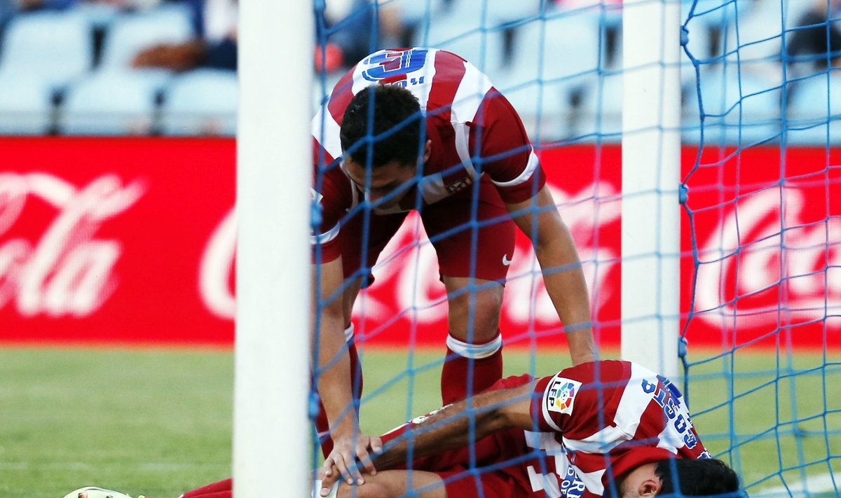 Atletico Madrid's Costa reacts in pain as his teammate Resurreccion Merodio bends down over him during their Spanish first division soccer match against Getafe in Getafe
