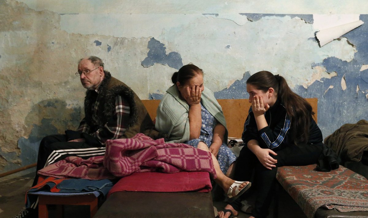 Local residents sit inside a bomb shelter where they are seeking refuge during what they say is shelling in Donetsk