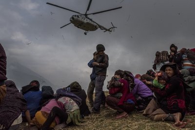 Nepaali külaelanikud vaatavad, kuidas helikopter korjab peale arstide meeskonna ja viskab alla abipakid. Gumda, Nepaal. Pildistatud 2015. aasta 9. mail.