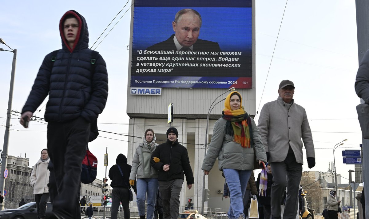 Пешеходы идут мимо экрана, транслирующего обращение Владимира Путина к Федеральному собранию