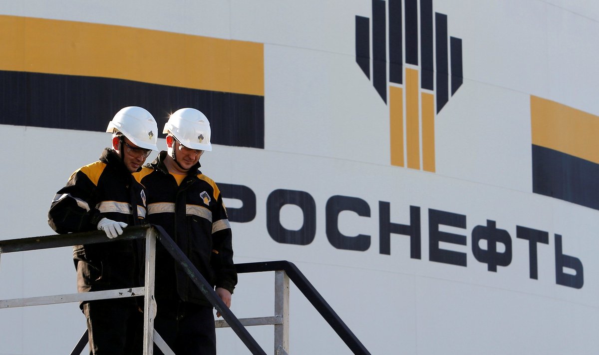 Workers stand next to logo of Russia's Rosneft oil company at central processing facility of Rosneft-owned Priobskoye oil field outside Nefteyugansk