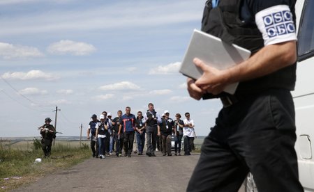 Monitors from OSCE and members of a forensic team visit the crash site of Malaysia Airlines Flight MH17 near the village of Hrabove