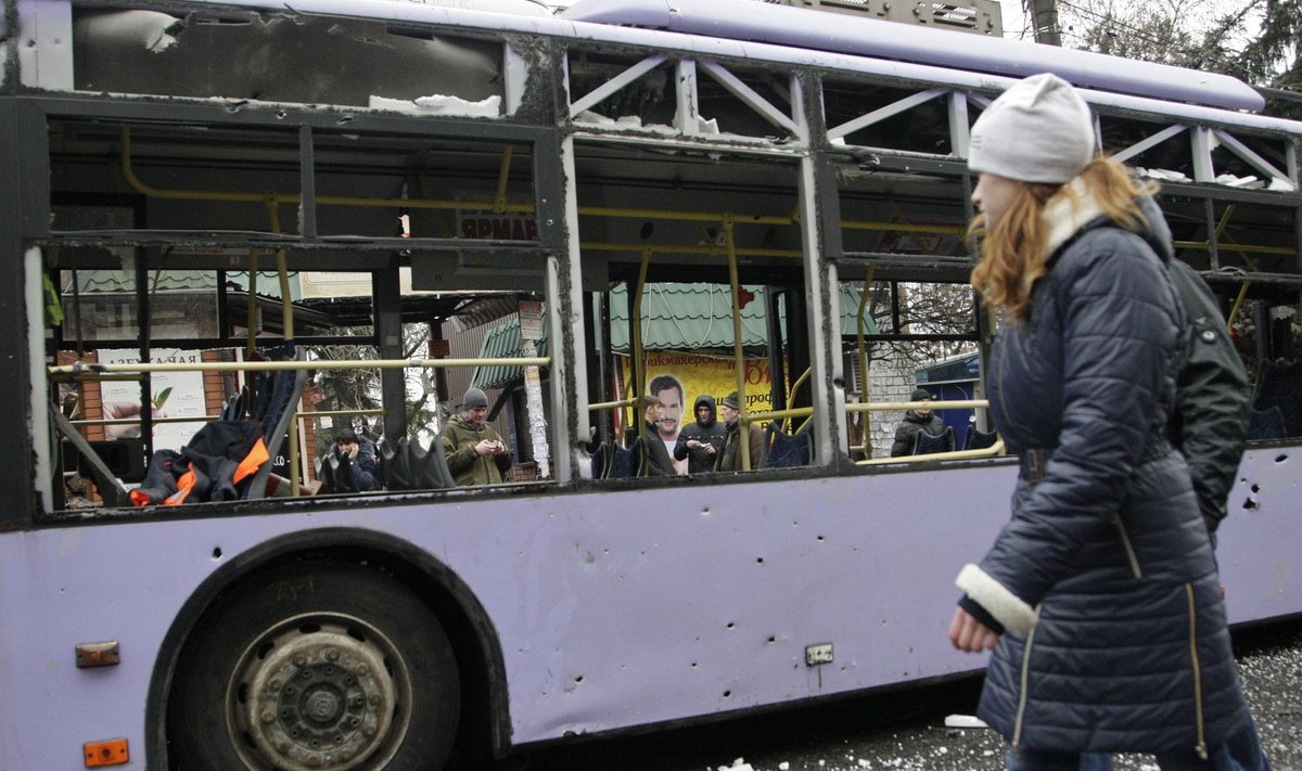 A woman walks past a damaged trolleybus in Donetsk