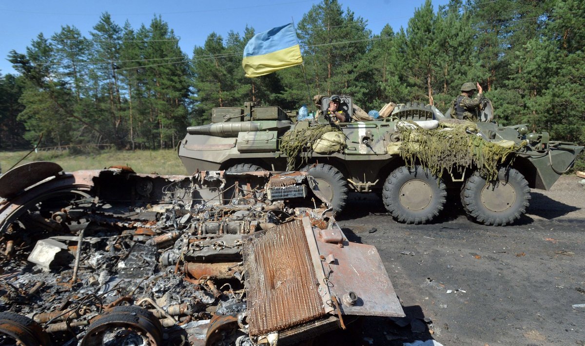 Ukraina lipuga soomusmasin möödub Slovjanski lähedal separatistide soomuki vrakist.
