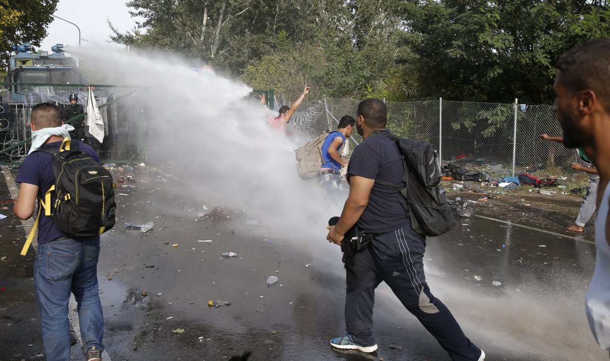 Migrants protest as Hungarian riot police fires tear gas and water cannon on the Serbian side of the border, near Roszke