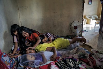Сестры и кузины окружили трехлетнюю Шиарини Таниа Тиранду, умершую днем ранее. Они гладят ее и говорят с ней. Для них она — то макула, больной человек. Фото: Брайан Лехманн