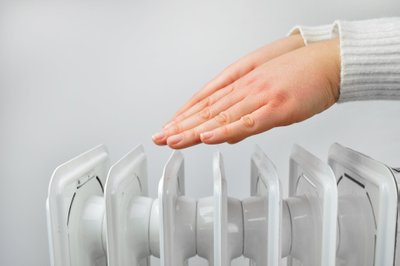 Woman,Gettin,Warm,Up,Her,Hands,Over,An,Electric,Radiator