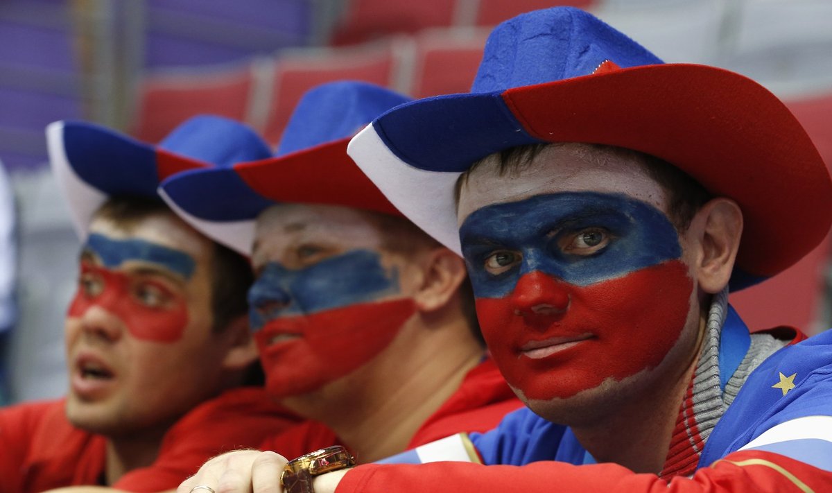 Fans with their faces painted in the colours of the Russian flag look on before the men's preliminary round ice hockey game between Russia and USA at the Sochi 2014 Winter Olympic Games