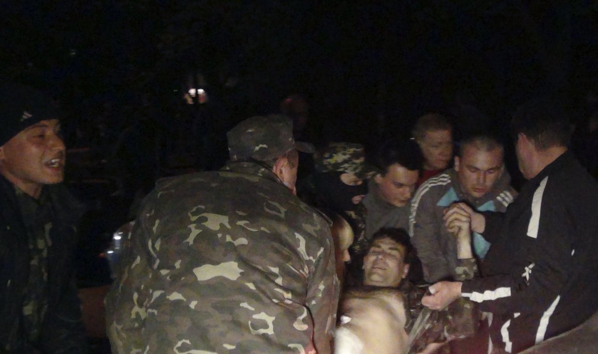People carry a man who was injured during pro-Russian protests near a Ukrainian military base in Mariupol