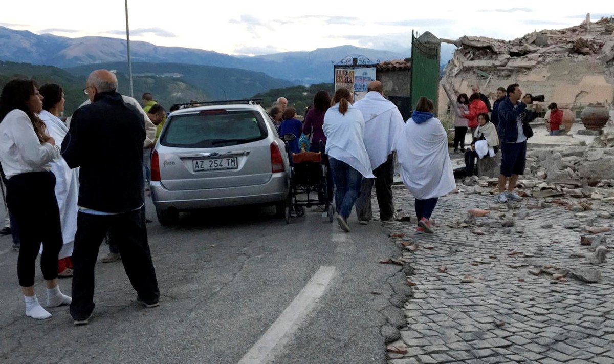 People stand along a road following a quake in Amatrice