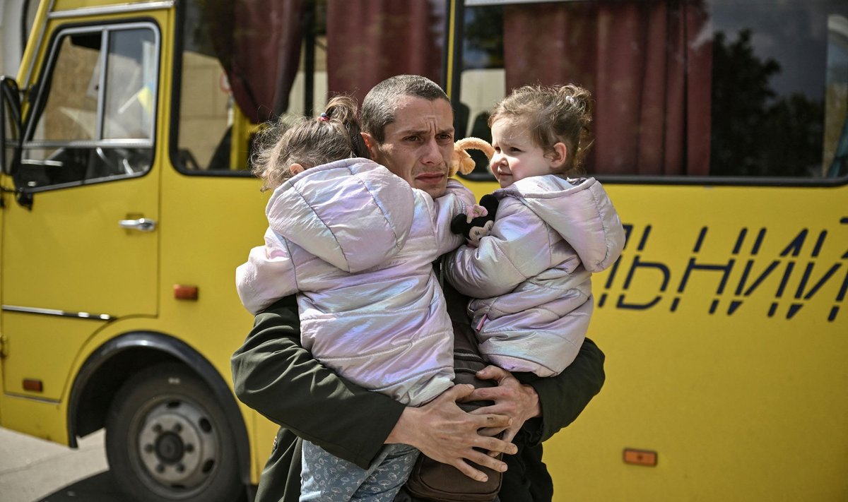 32-летний Дмитрий Мосур, потерявший жену во время обстрела Северодонецка 17 мая, держит на руках двухлетних дочерей-двойняшек, ожидающих эвакуации из Лисичанска