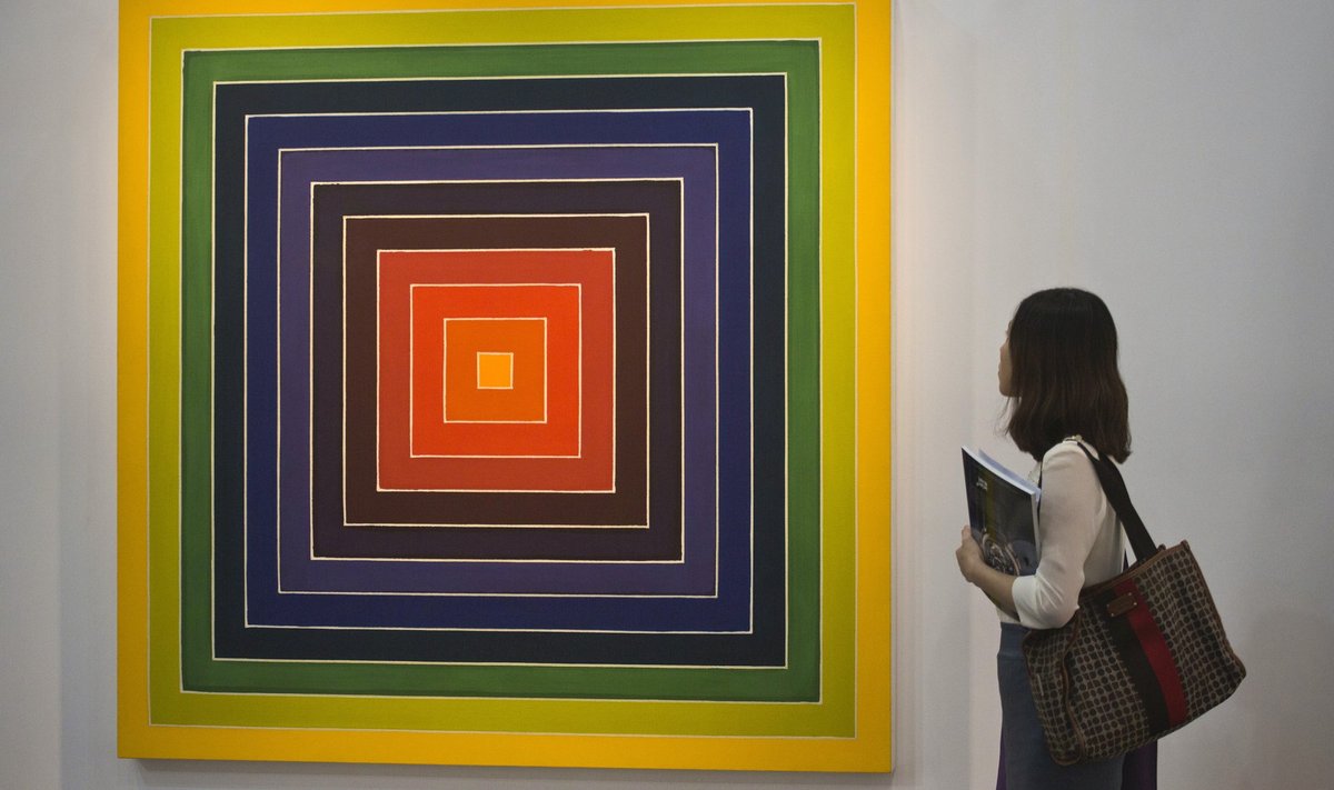 A woman observes painting "Mrs. Rabbit's Rainbow III" by U.S. artist Stella during a preview of the first Art Basel in Hong Kong