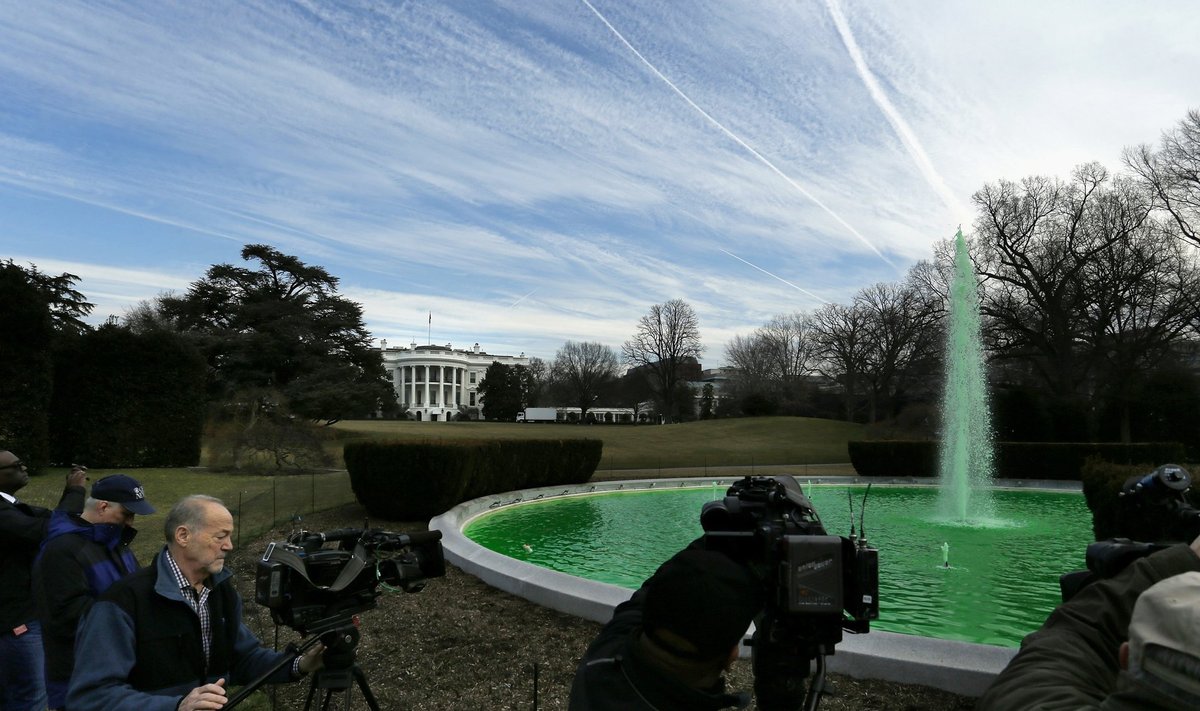 Video journalists shoot footage of the green water in the fountain on the South Lawn of the White House, which was dyed in celebration of St. Patrick's Day in Washington
