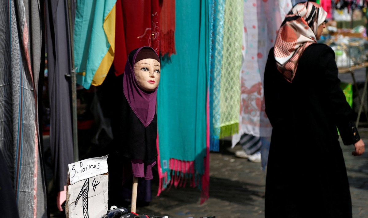 Naine kõnnib turul mööda hidžaabi kandvast mannekeenist
