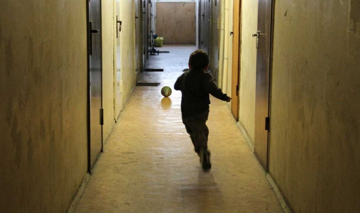 Väike poiss mängib ühiselamus, oma kodu koridoris, oma mängumaal.