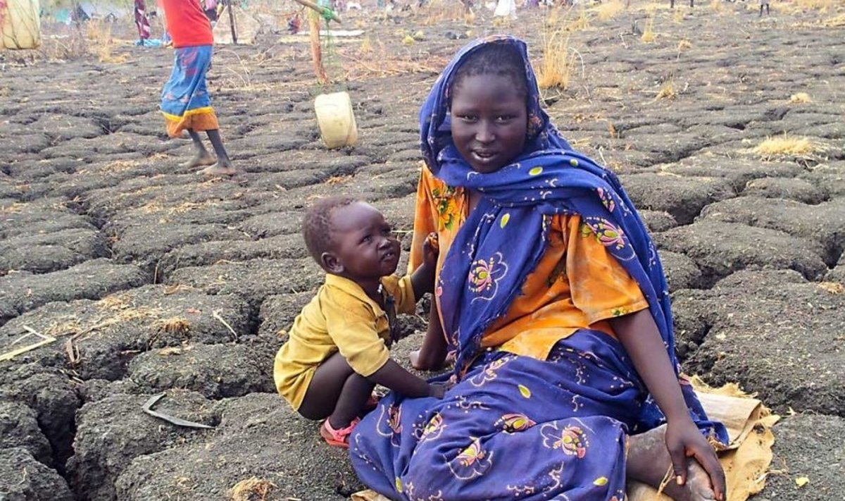 Päiksest kõrbenud maa: mais ületab õhutemperatuur Lõuna-Sudaanis sageli 40 kraadi. Maapind lõheneb ning tekkinud pragudes otsivad päevase kuuma eest varju skorpionid ja maod. Fotol puhkavad Sudaanist põgenenud ema ja laps jalga Rum’i transiitpunktis. (Foto: Krister Kivi)