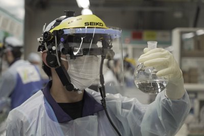 Лаборанты в здании химического анализа на АЭС „Фукусима-1“ анализируют образцы воды. Они используют „умные очки“ для записи данных об образцах и общения с другими членами команды. АЭС „Фукусима“. Япония, 2022 г