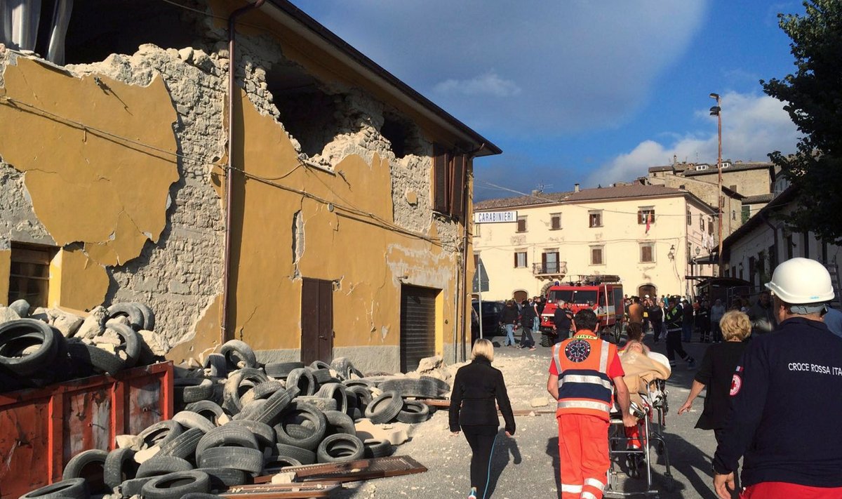 Rescuers and people walk along a road following an earthquake in Accumoli di Rieti, central Italy