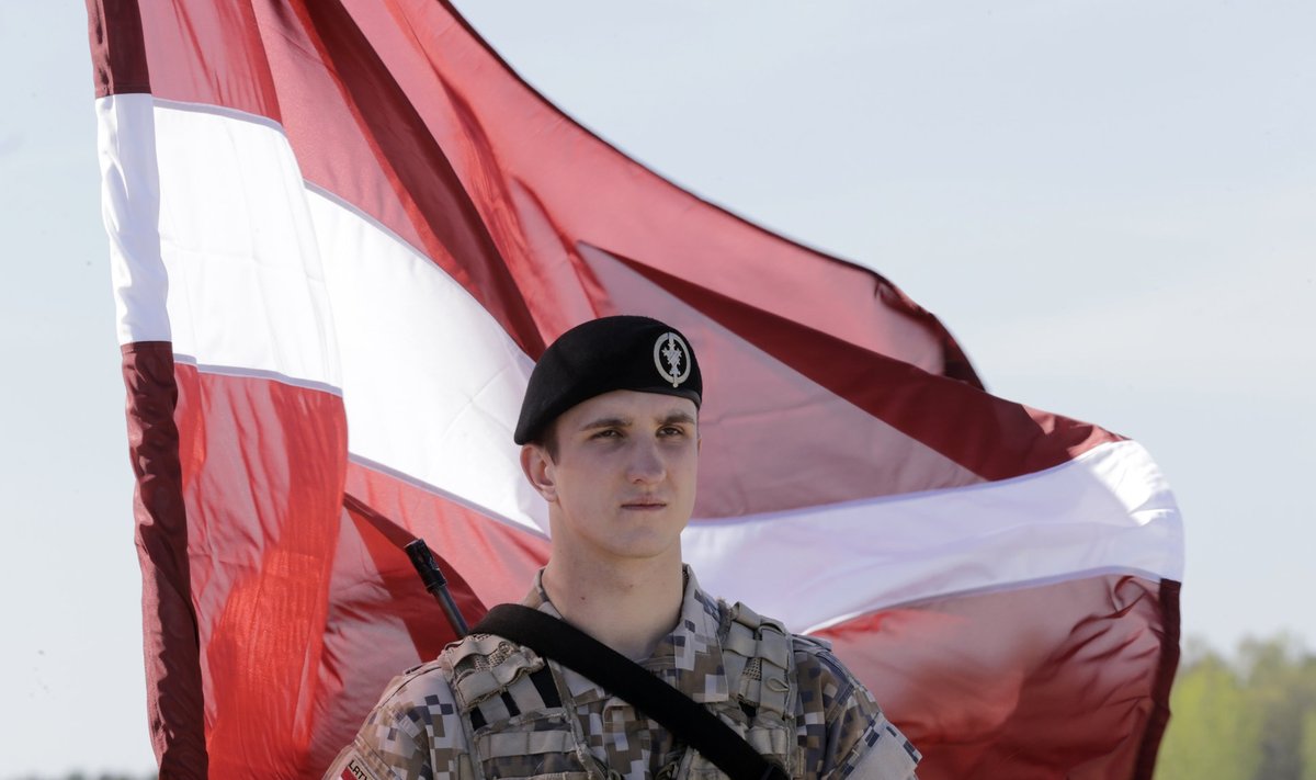 A Latvian soldier holds a national flag as he waits for about 150 U.S. paratroopers from the U.S. Army's 173rd Infantry Brigade Combat Team based in Italy to arrive in the airport in Riga