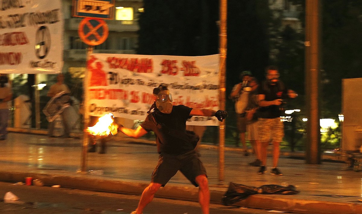 A masked youth hurls petrol bomb to riot police during clashes in Athens