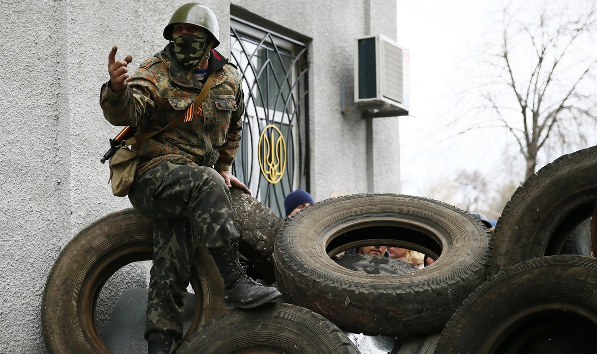 An armed man gestures from a barricade in front of the police headquarters in Slaviansk