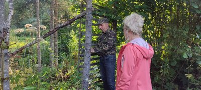 Meelis Reinart päästab žürii ulukitõrjeks rajatud aia väravast männikultuure vaatama.