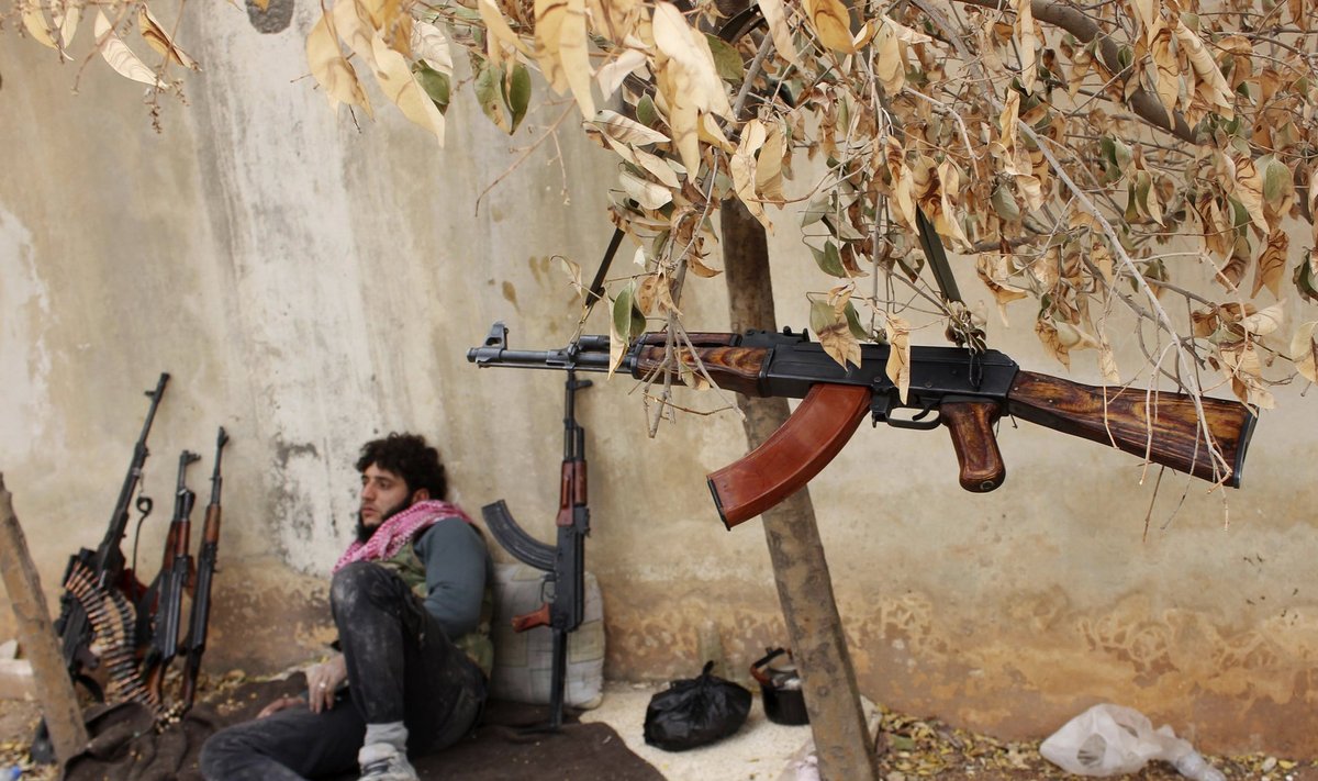 A fighter from the Tawhid Brigade, which operates under the Free Syrian Army, rests by the weapons of his fellow fighters near the 80th Brigade base in Aleppo