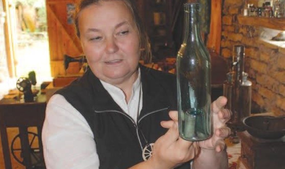Kersti Pent näitamas pudelikollektsioonist eksemplari. “Igavene suur pudel, aga mida suurem punn all on, seda vähem ju vedelikku sisse mahub,” räägib ta, miks pudelipõhjas olevat tühimikku petjaks kutsutakse.