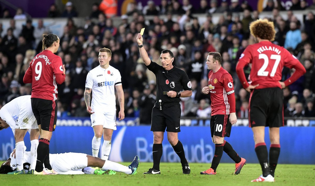 Manchester United's Zlatan Ibrahimovic is shown a yellows card by referee Neil Swarbrick as Swansea City's Leroy Fer is down holding his face