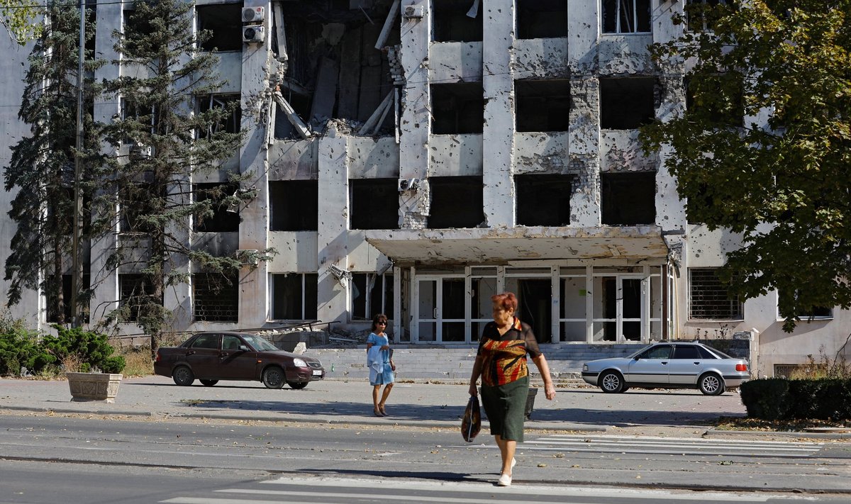 Inimesed kõnnivad Mariupolis sõjategevuse käigus kannatada saanud hoone lähedal. 
