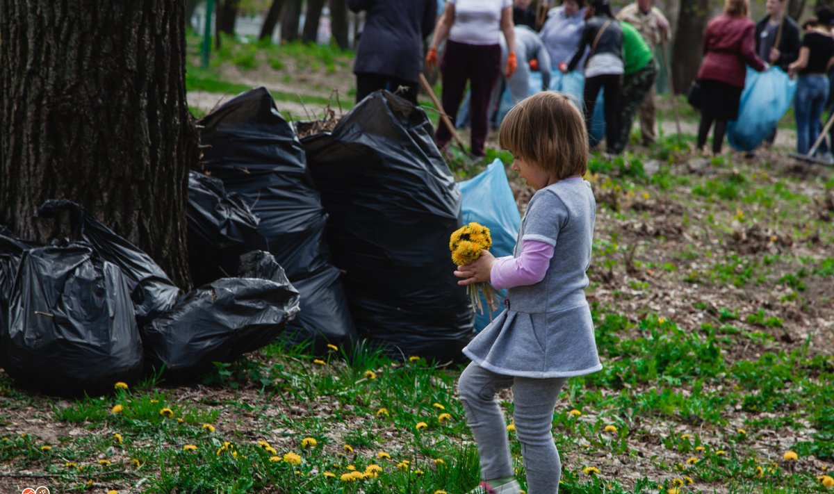  Украина. Маленькая девочка собирает одуванчики, а сзади кипит работа по уборке мусора