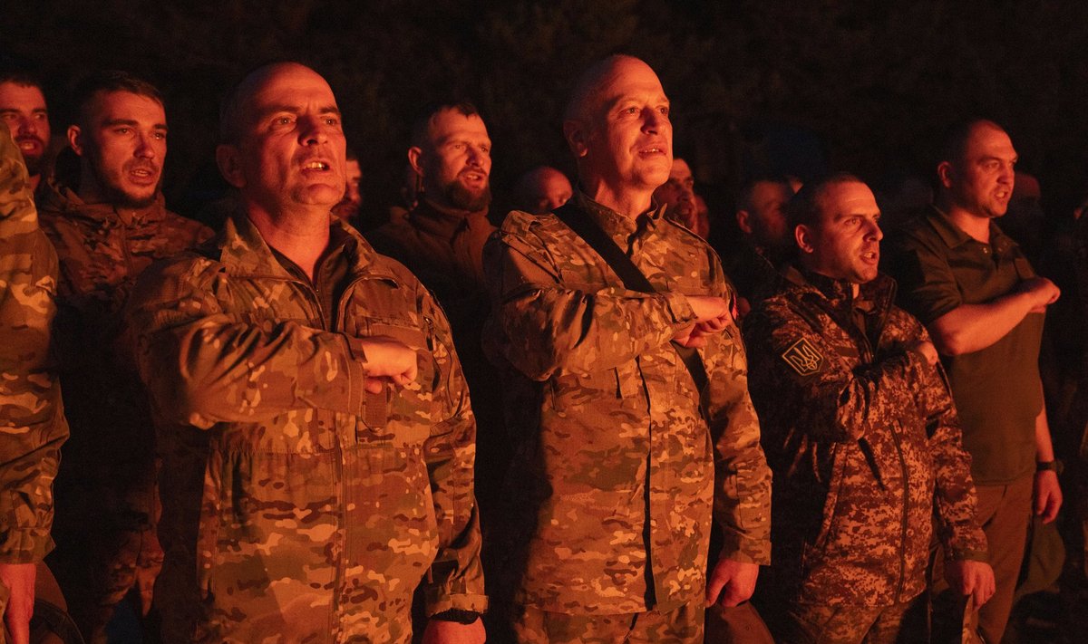 Солдаты 3-го батальона Национальной гвардии Украины "Свобода" бригады "Рубеж" молятся, стоя у костра во время ротации в Киевской области, Украина, 11 апреля 2024 года.