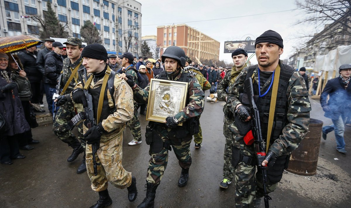 Armed pro-Russian protesters escort a comrade who is carrying an icon, which they said was found in the seized office of the SBU state security service, in Luhansk