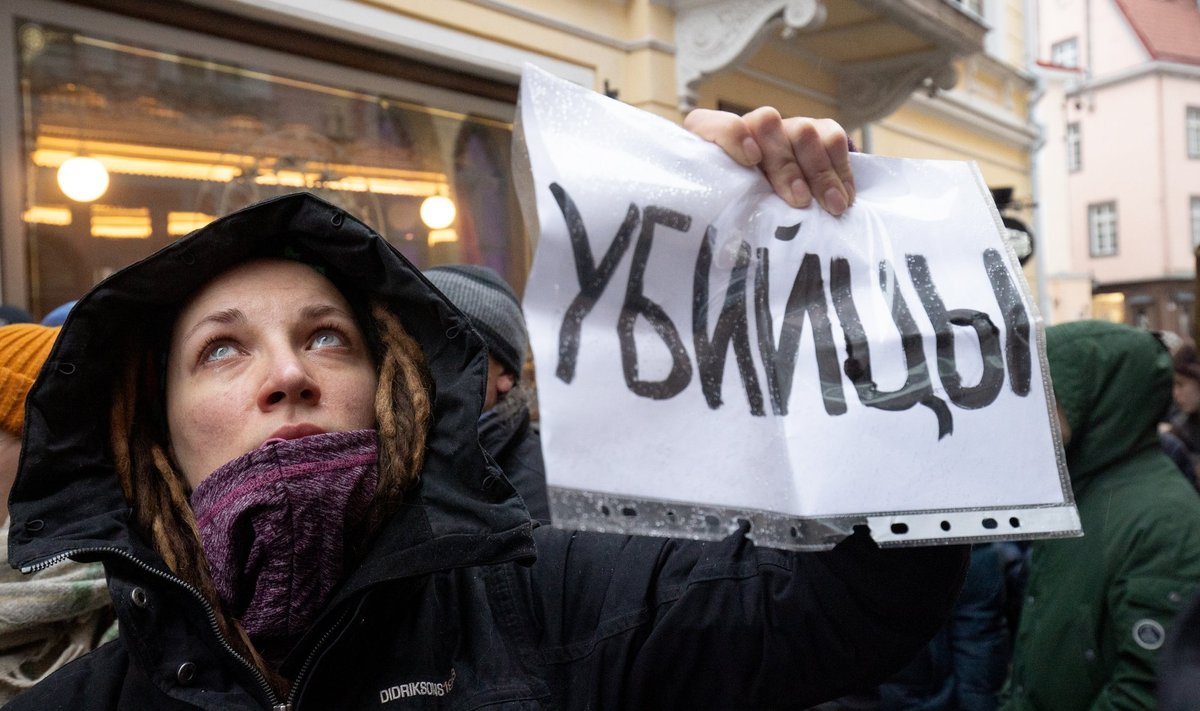 Женщина показывает плакат с надписью "Убийцы" в окна российского посольства, 16.02.2024