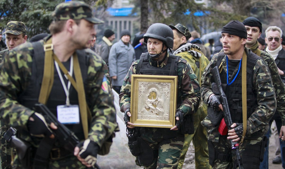 Armed pro-Russian protesters escort a comrade who is carrying an icon, which they said was found in the seized office of the SBU state security service, in Luhansk