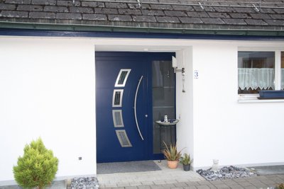 Julge värvilahendus, kus valge maja on saanud omanäolise disainiga sinist värvi ukse.