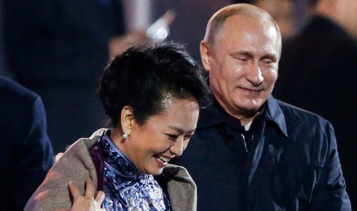 Russia's President Putin helps put a blanket on Peng, wife of China's President Xi, in Beijing