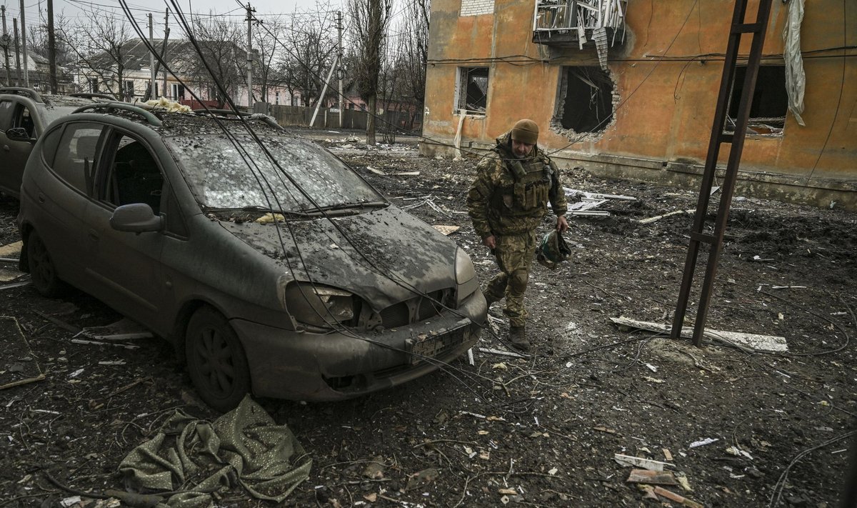 Украинский военный осматривает то, что осталось от машины после обстрела Часова Яра.