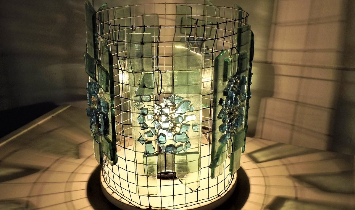 Silindrikujulist traatvõrgust valgustit kaunistavad sulatatud klaasitükid.