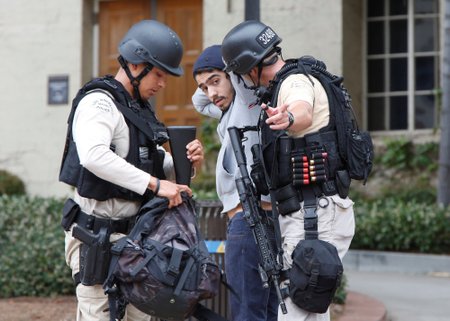 Police officers search a student's belongings at the University of California, Los Angeles (UCLA) campus after it was placed on lockdown following reports of a shooter in Los Angeles