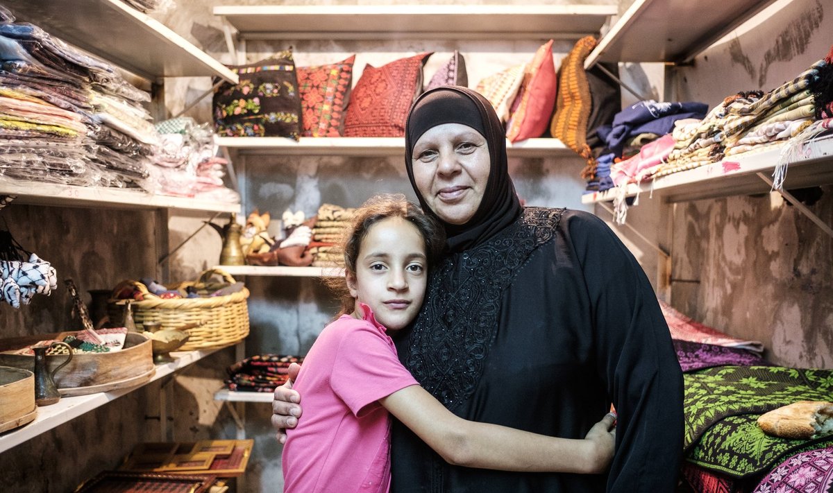 Leila Awawdeh lapselapsega oma poe uksel. Awawdeh ei julge Hebronist lahkuda, sest tagasi tulles ei pruugi ta enam oma majja pääseda.