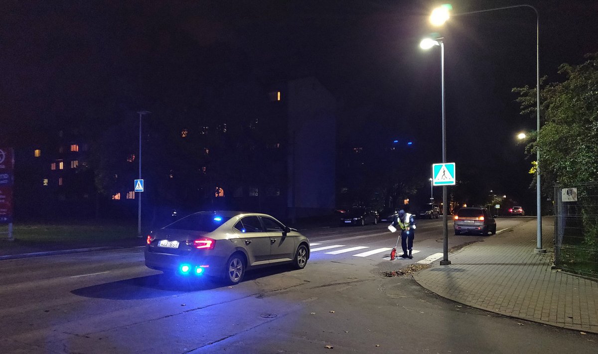 Politseinik õnnetuspaigal J.Smuuli tänaval ülekäiguraja juures mõõtmisi tegemas.