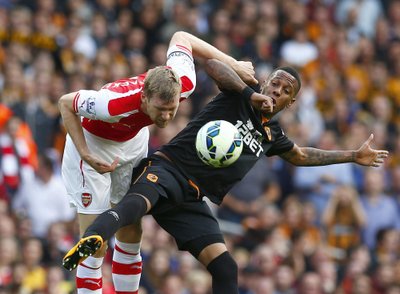 Arsenal's Per Mertesacker challenges Hull's Abel Hernandez during their English Premier League soccer match at the Emirates stadium in London