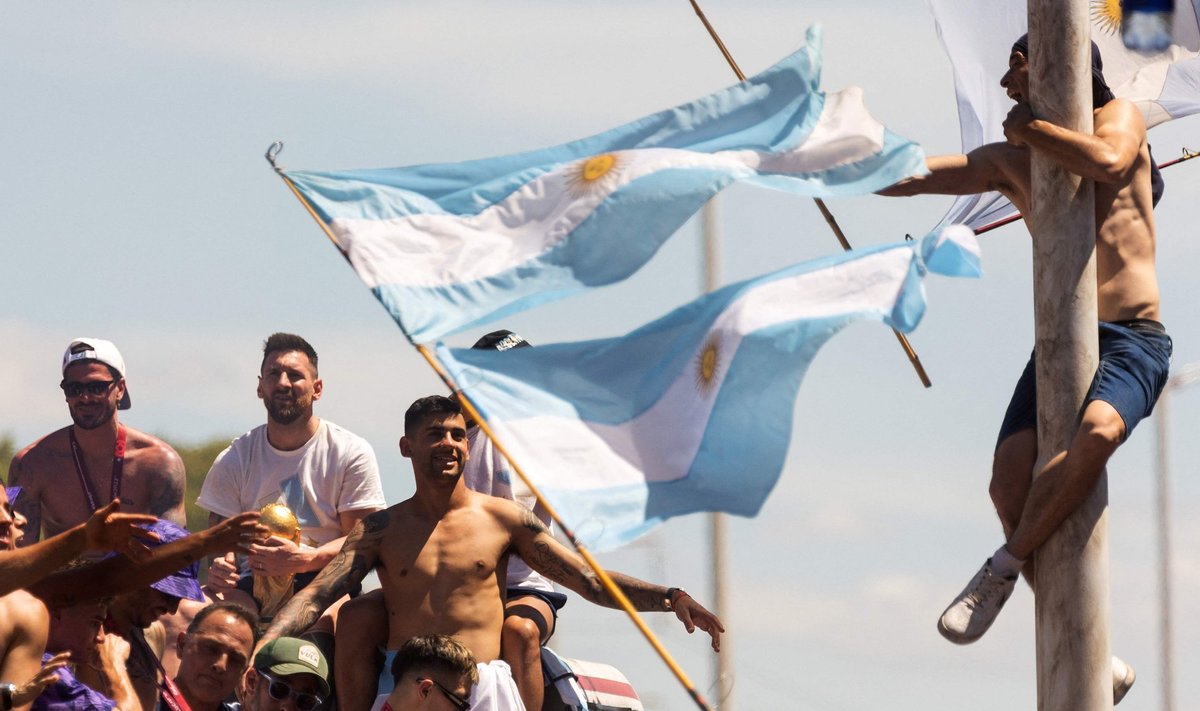 Болельщик взбирается на фонарный столб (справа) на параде сборной Аргентины.