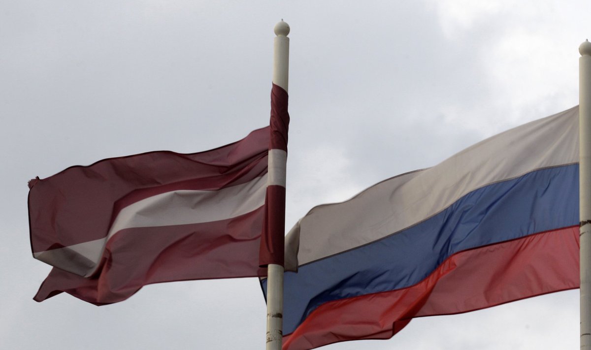 A Latvian flag flutters in the wind next to a Russian flag near a hotel in Daugavpils