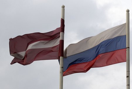 A Latvian flag flutters in the wind next to a Russian flag near a hotel in Daugavpils