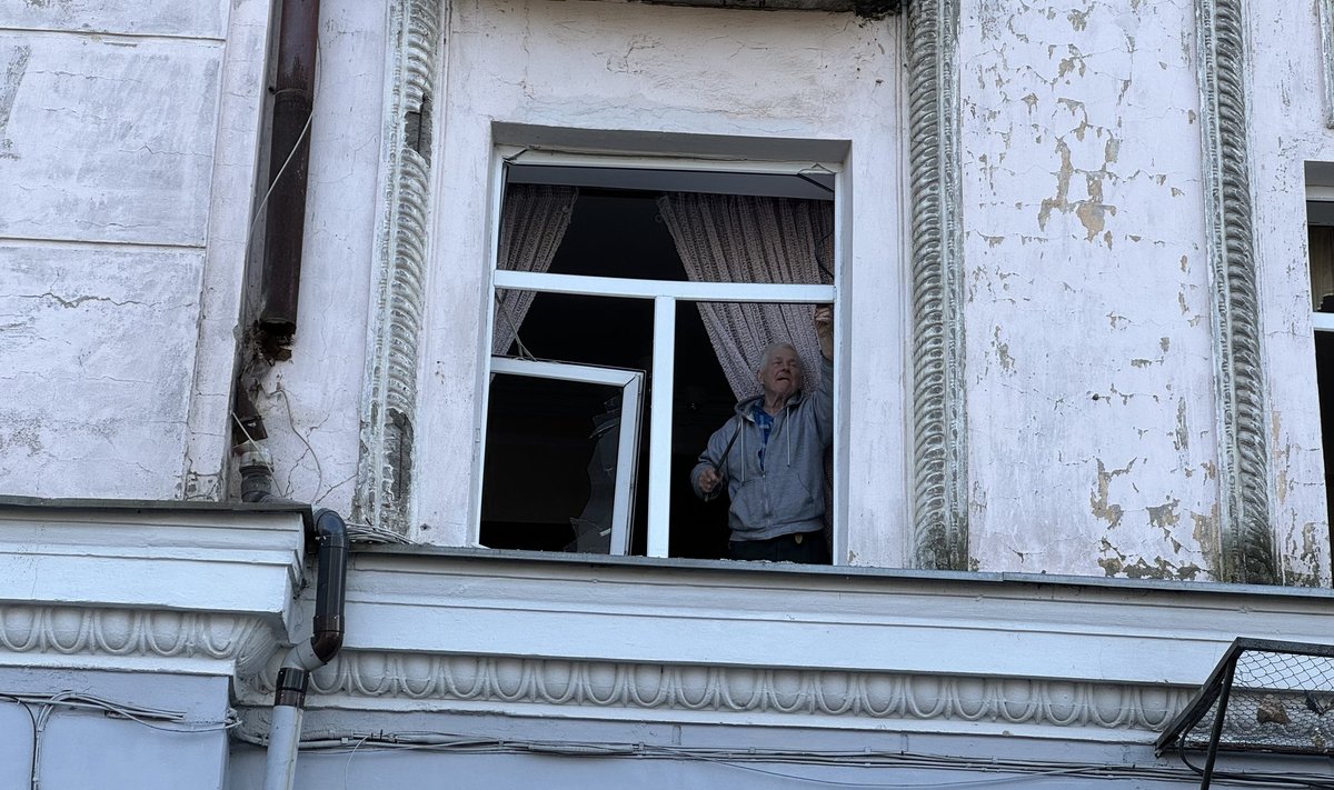 Мужчина возле окна дома в Киеве, подвергшегося российским обстрелам, 21 марта 2024 года.