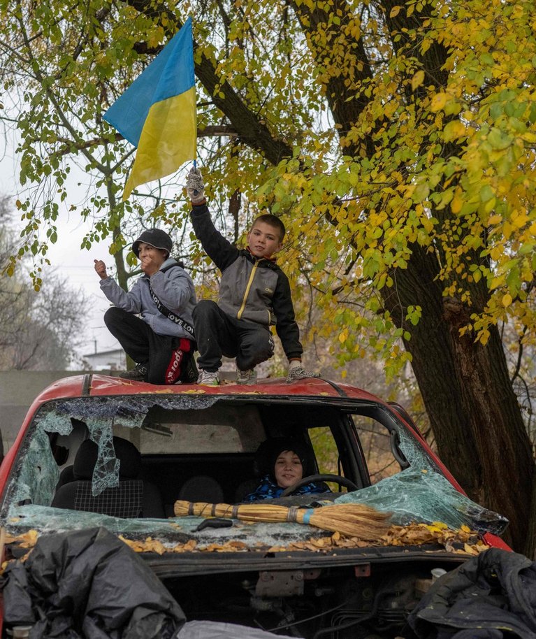 Kohalikud elanikud hävitatud autol tähistamas Hersoni vabastamist. Foto tehtud 13. novembril 2022.